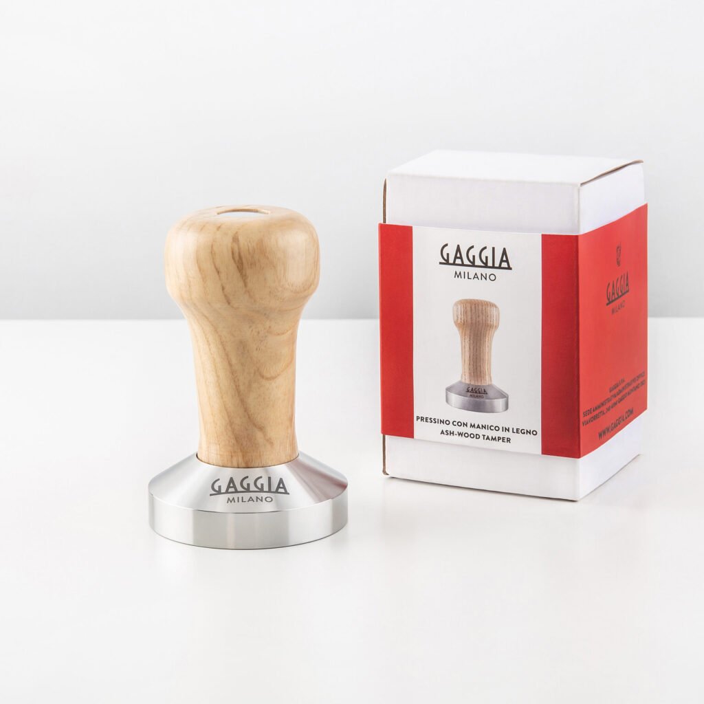 Tamper Gaggia Milano à poignée en bois de frêne à côté de sa boîte