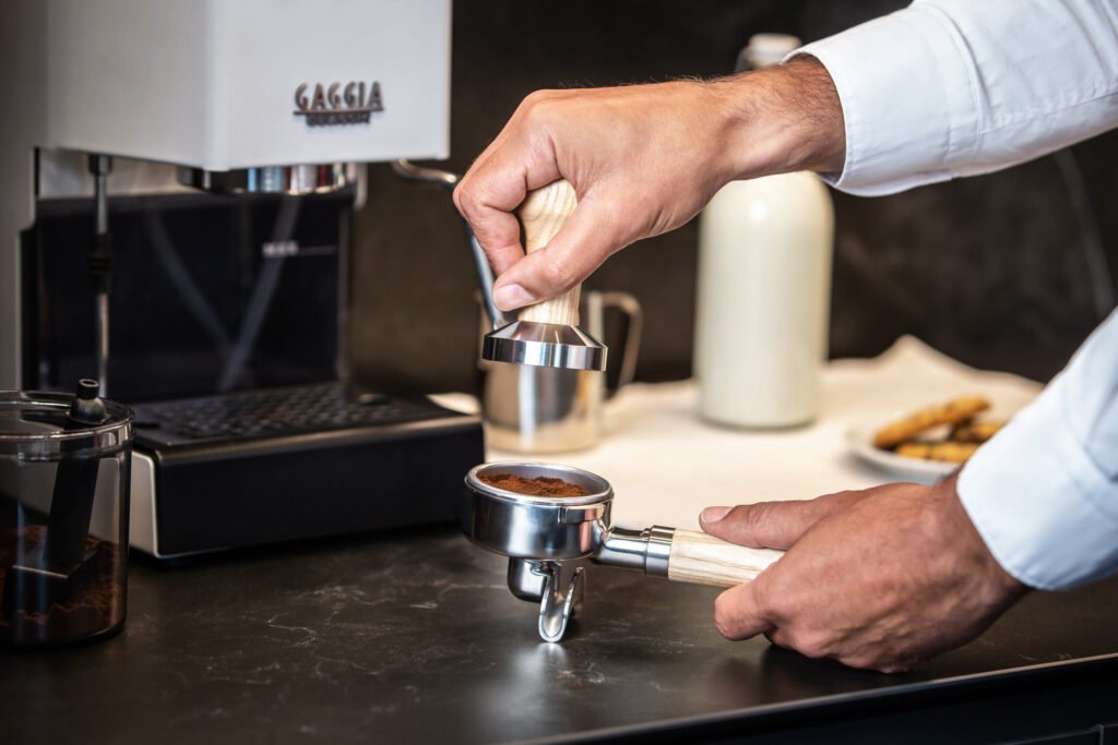 Tassage du café dans le porte-filtre devant une Gaggia Classic E24 blanche