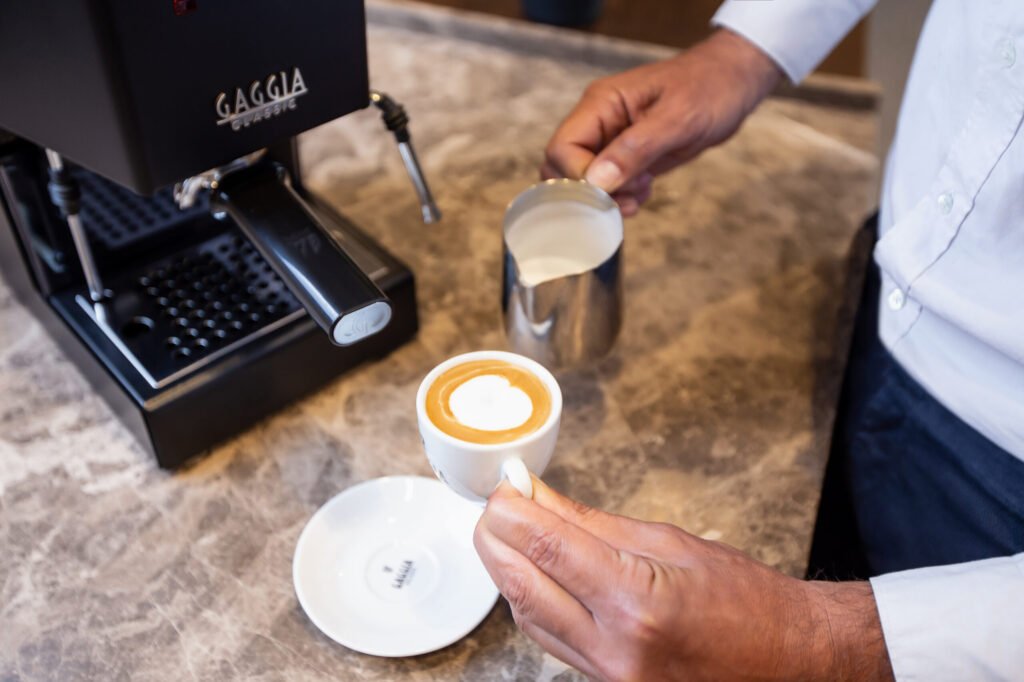 Latte art versé dans une tasse à côté d'une Gaggia Classic Pro E24 noire